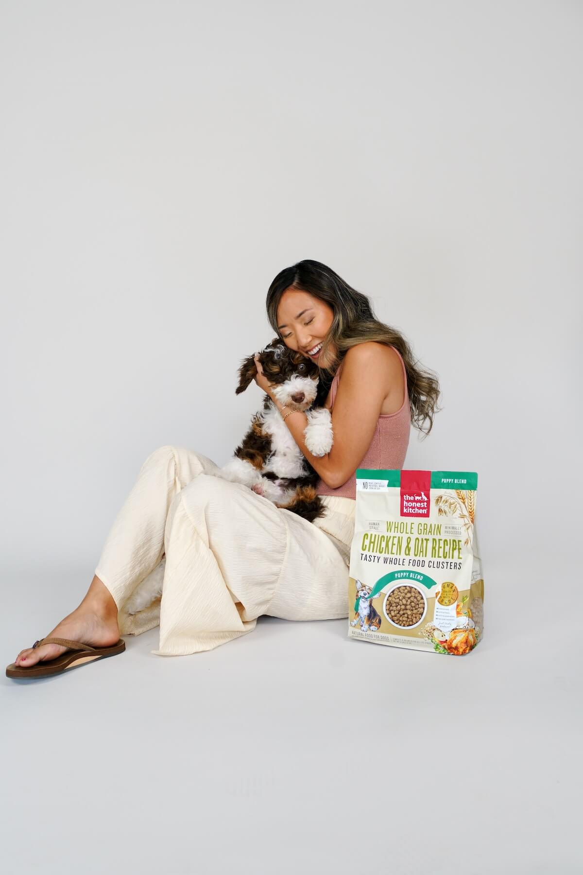 The Honest Kitchen: Woman cuddling dog next to dog food bag