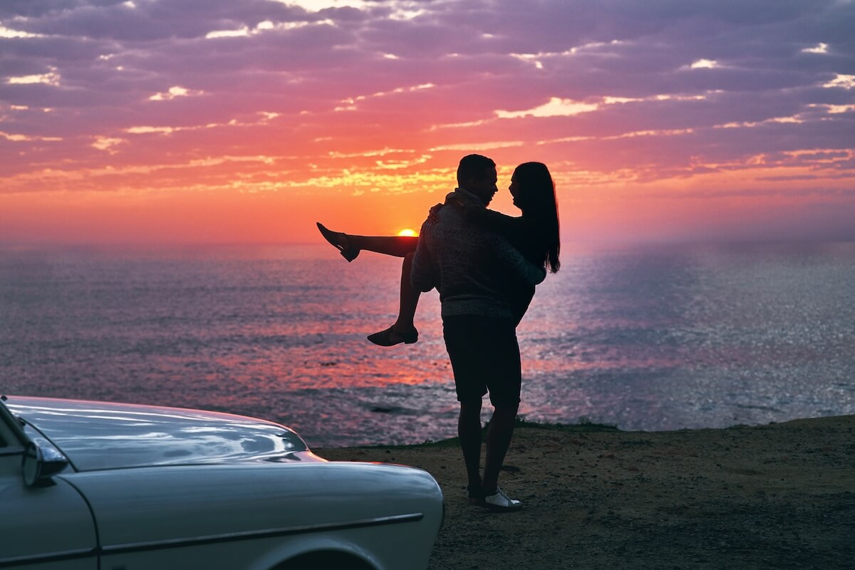 Shutterstock: Couple, carrying and love with beach sunset for holiday, embrace or outdoor weekend together in nature, Silhouette, man and woman with care for vacation, travel or road trip on date by ocean coast