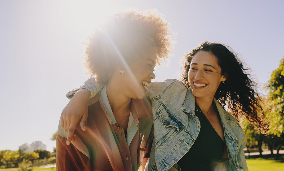 Shutterstock: Two best friends laughing and enjoying each other's company on a summer's day in the park. Happiness and friendship in a natural outdoor setting.