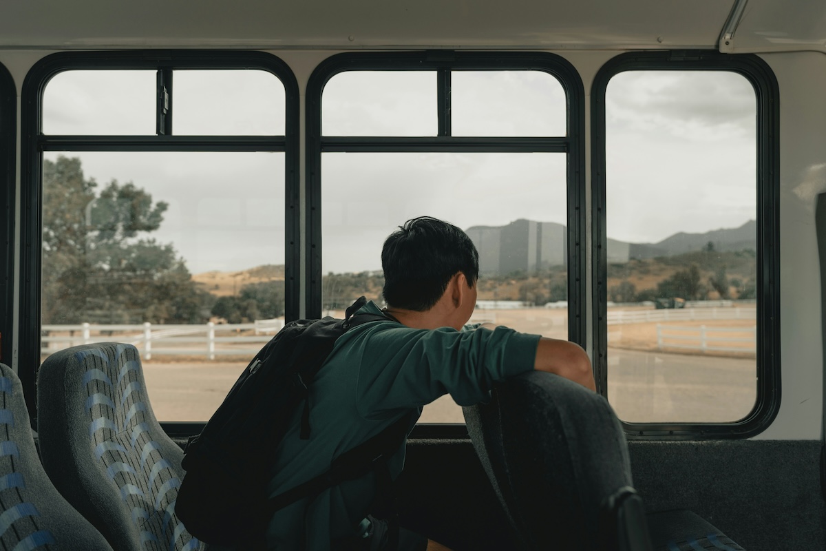 Unsplash: Man looking out bus window by Clay Banks