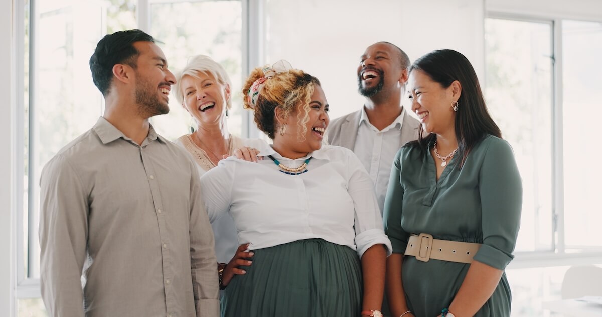 Shutterstock: Success, happy or funny business people in an office building laughing at a funny joke after a group meeting. Diversity, comic or employees with big smiles bonding after a successful business deal