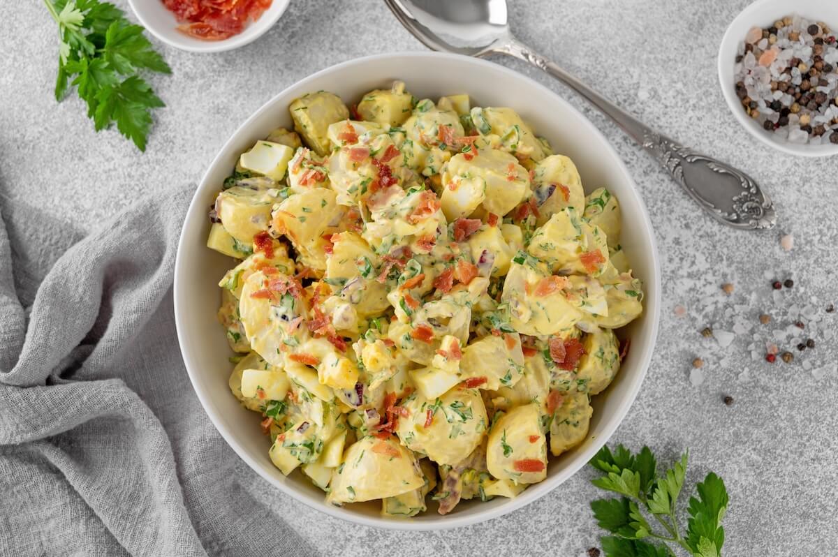 Shutterstock: Salad of potatoes, eggs, bacon and fresh herbs with mayonnaise and yogurt dressing in a bowl on a gray concrete background