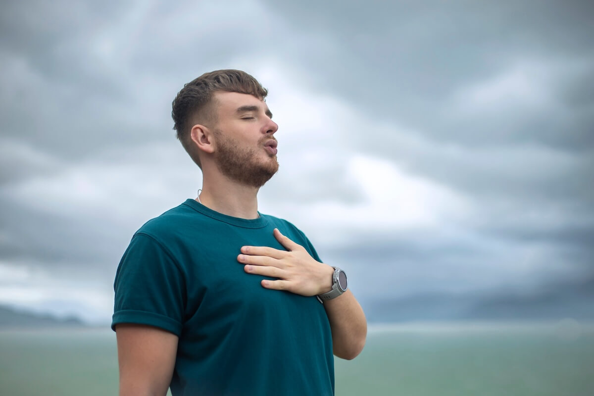 Shutterstock: happy handsome free guy, young calm relaxed carefree man traveler with open raised hands enjoy sea, ocean view, person feeling good, breath deep deeply fresh air. Freedom, travel, happiness concept