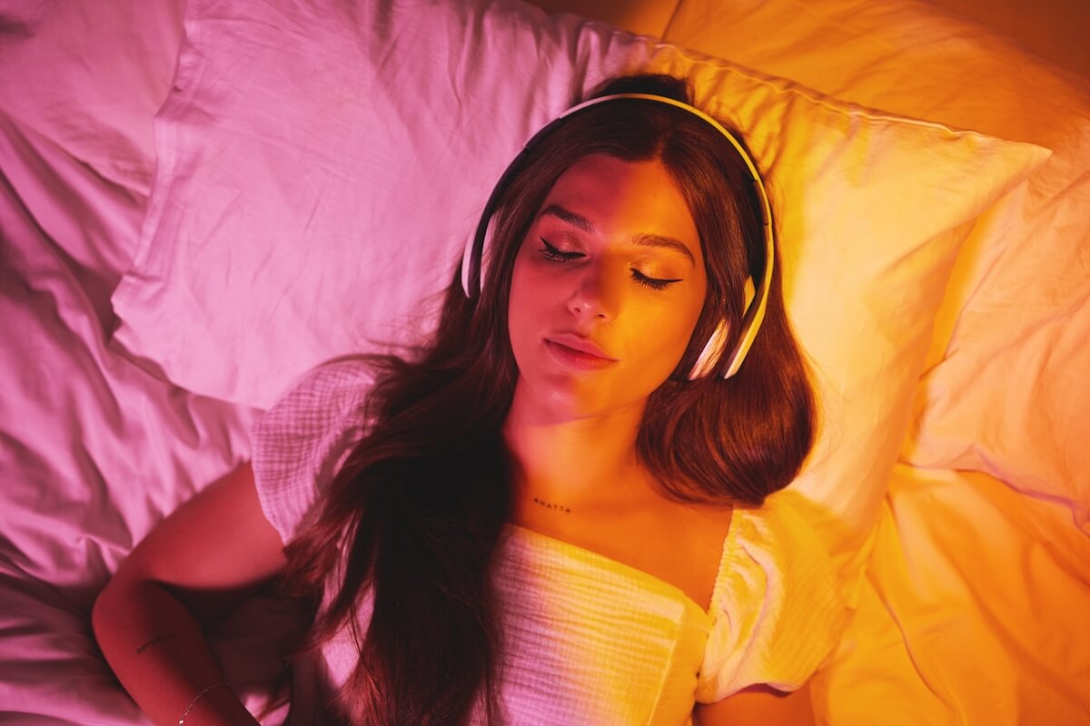Shutterstock: Gen z, headphones and woman sleeping with creative vaporwave lighting in a bedroom bed. Dreaming, music listening and web audio streaming of a female model resting eyes with makeup on a pillow