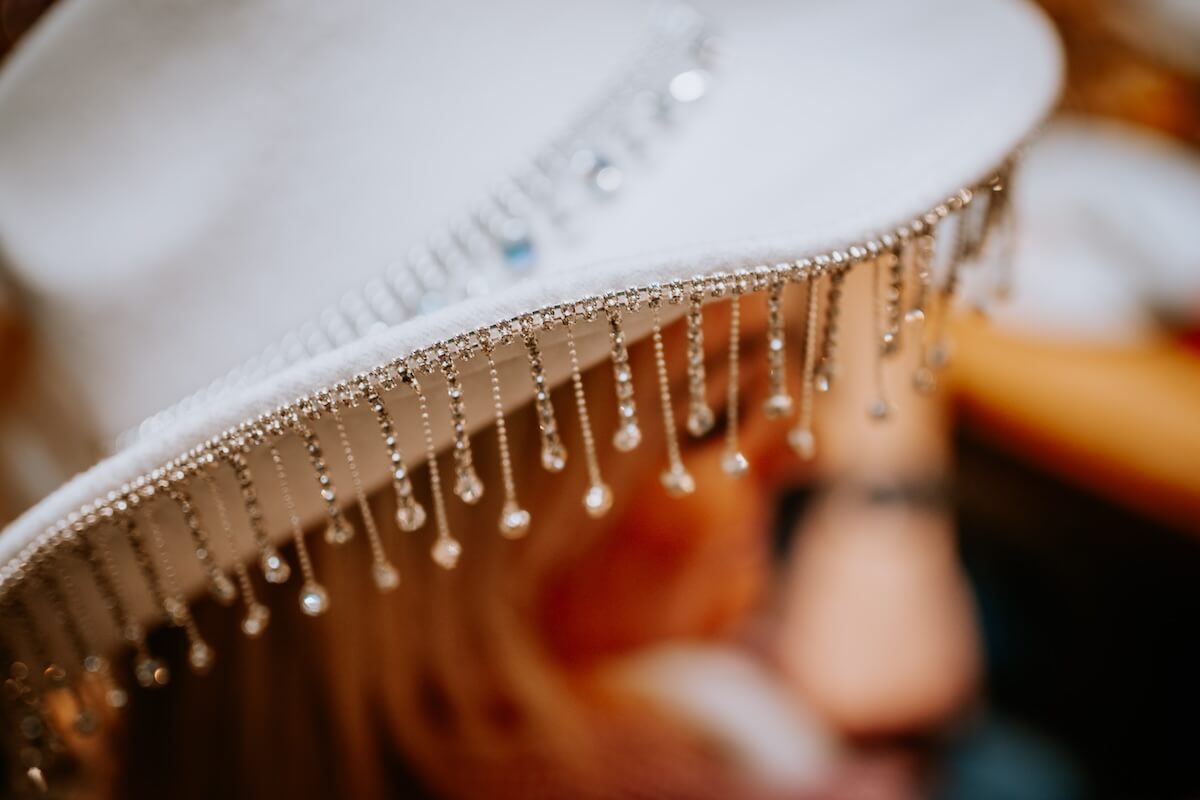 Shutterstock: Madona, Latvia - February 15, 2025 - Close-up of a white cowboy hat adorned with sparkling rhinestone fringe details, showcasing texture and luxury in western fashion. Blurred background for depth.