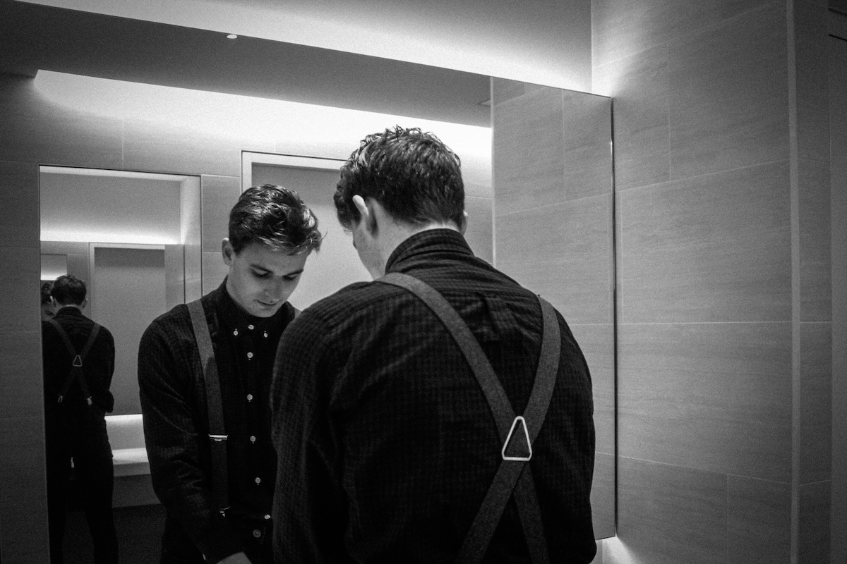 Unsplash: Man in suspender looking in mirror by Hannah Reding