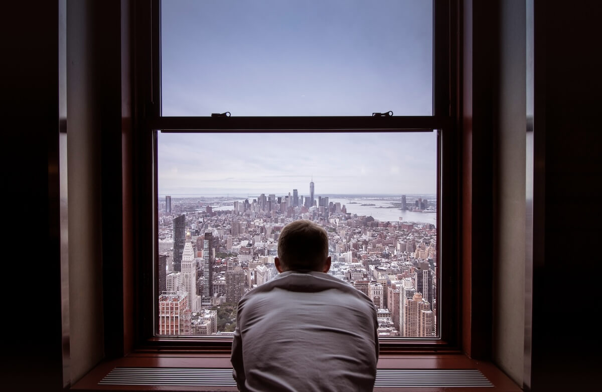 Unsplash: Man looking out windows at city by norbert kundrak