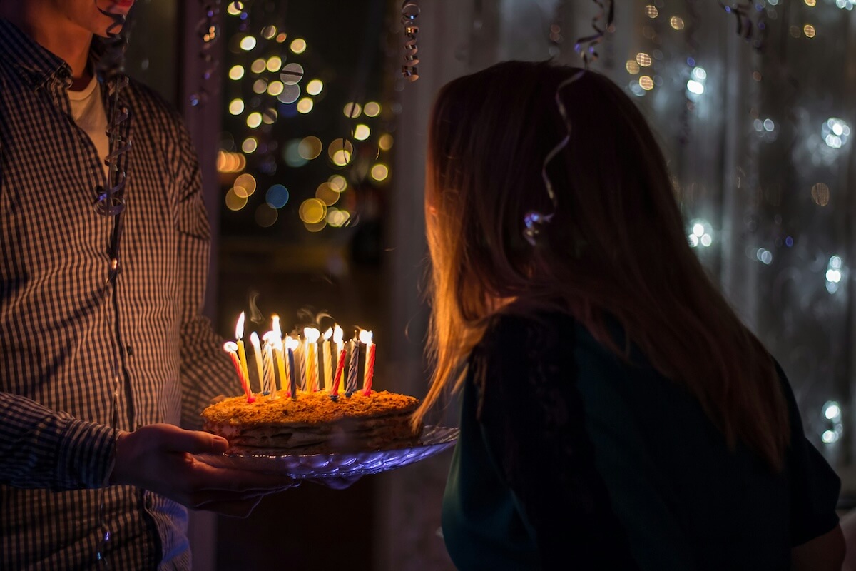 Unsplash: Woman blowing out candles on chocolate cake by Sergei Solo