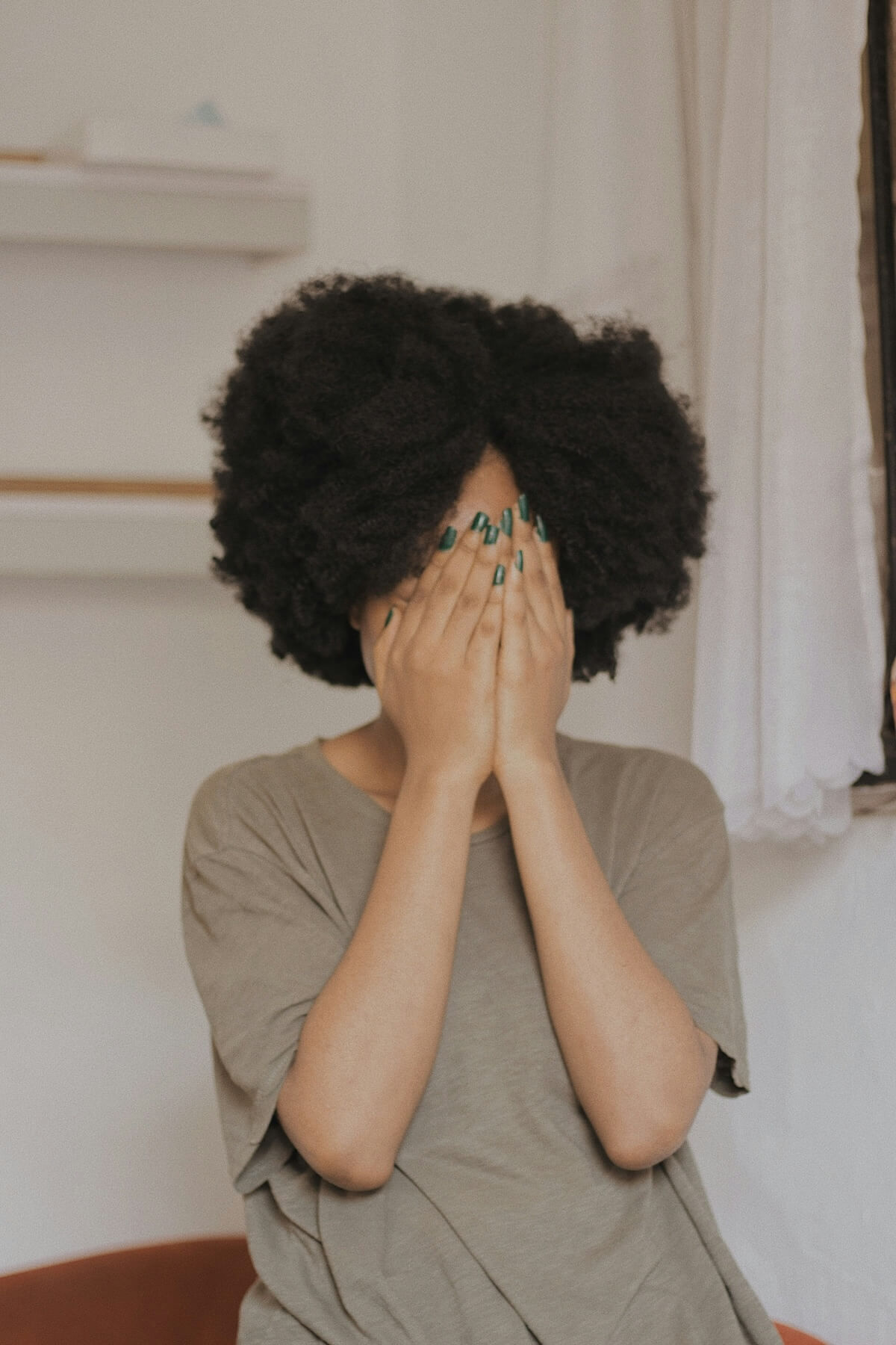 Unsplash: Woman covering face with hands and shy by Baptista Ime James