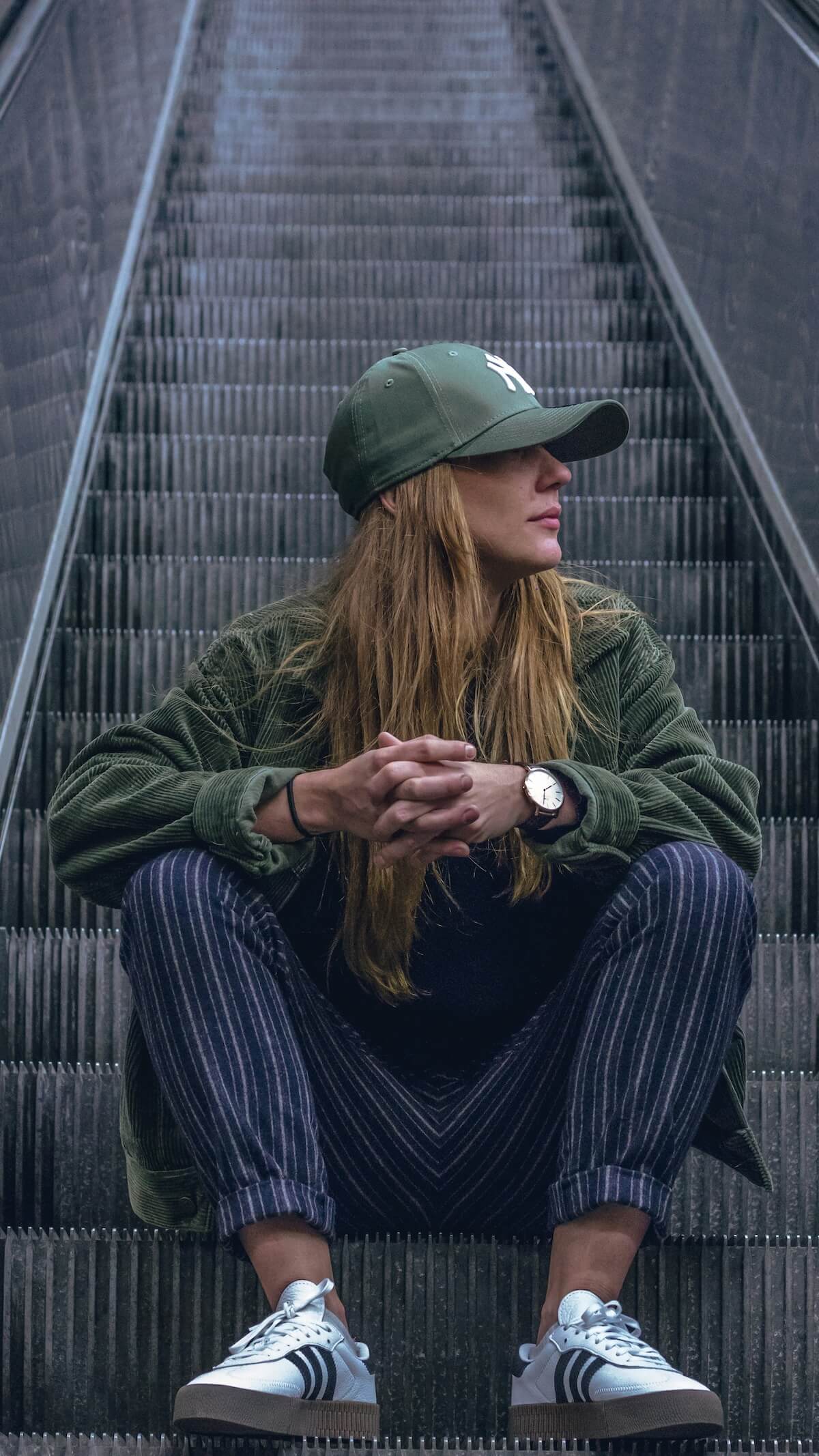 Unsplash: Woman in baseball cap sitting on escalator by Maureen de Wit