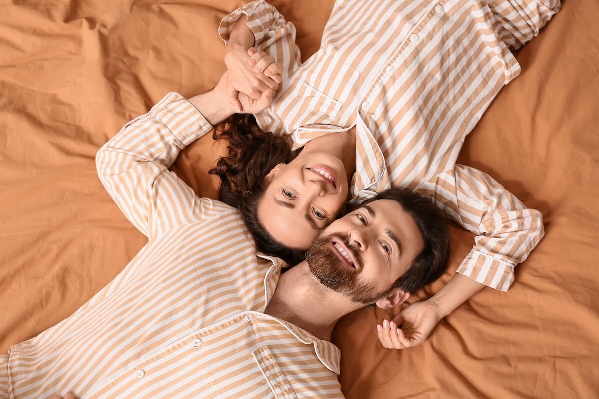 Shutterstock: Happy couple in pajamas lying on bed, top view