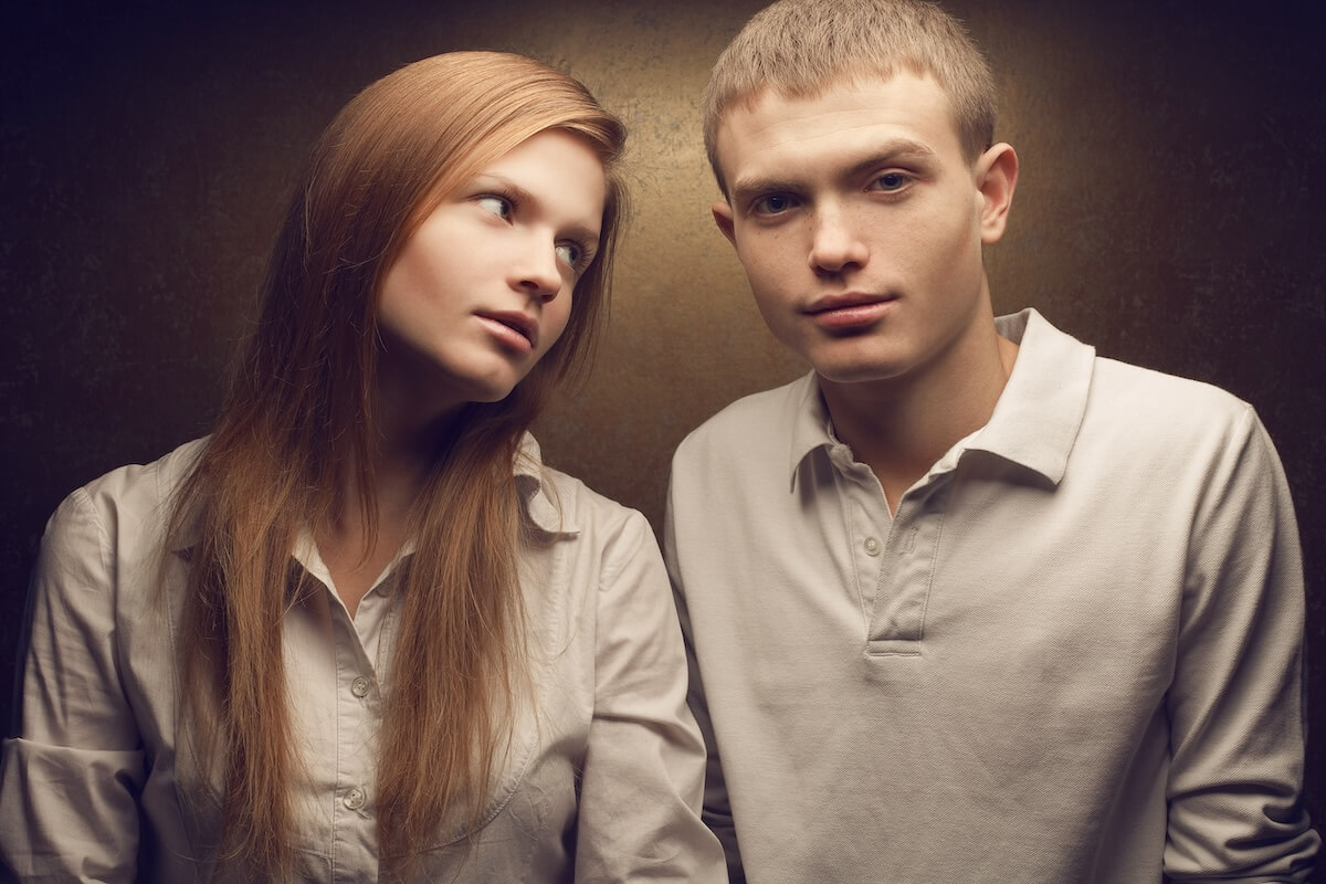 Shutterstock: Emotive portrait of gorgeous red-haired fashion twins in white shirts posing over golden background together. Studio shot.
