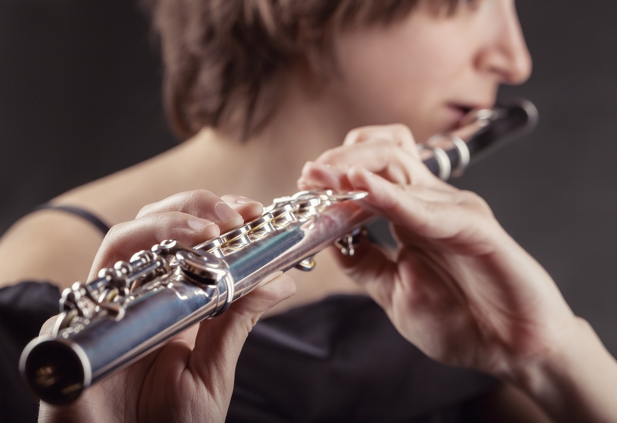 Shutterstock:Close-up of a woman playing the flute on black background