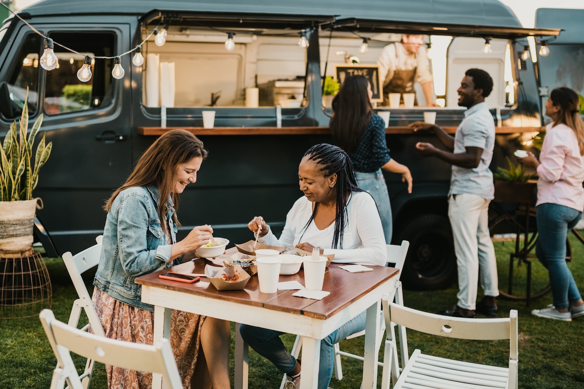 Shutterstock: Diverse women having lunch in park near food truck