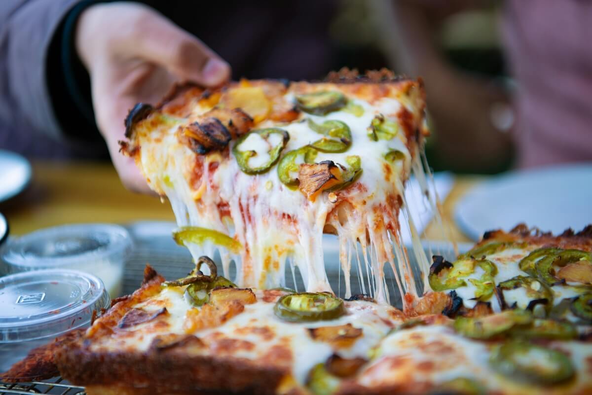 Unsplash: Pulling slice of jalapeño pizza by Akshaya Jayaprakash