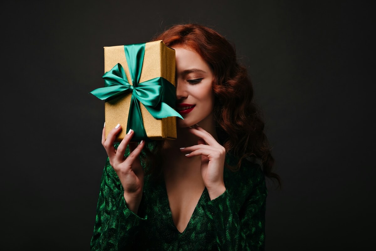 Unsplash: Red haired woman holding wrapped gift by look studio