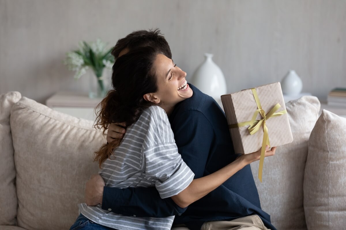Shutterstock: Happy young 30s latina woman embracing loving husband, feeling thankful for getting present in wrapped gift box, celebrating happy birthday or marriage anniversary, international women s day.