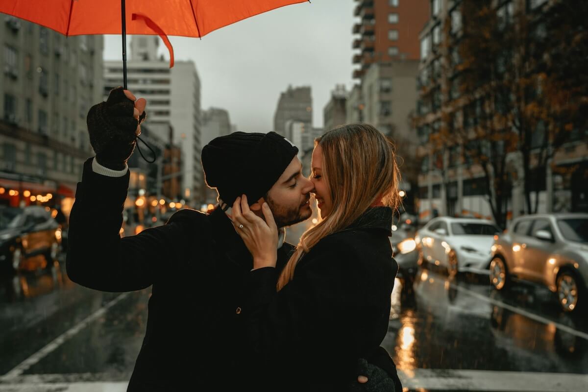 Unsplash: Couple moving for kiss under umbrella by Clay Banks