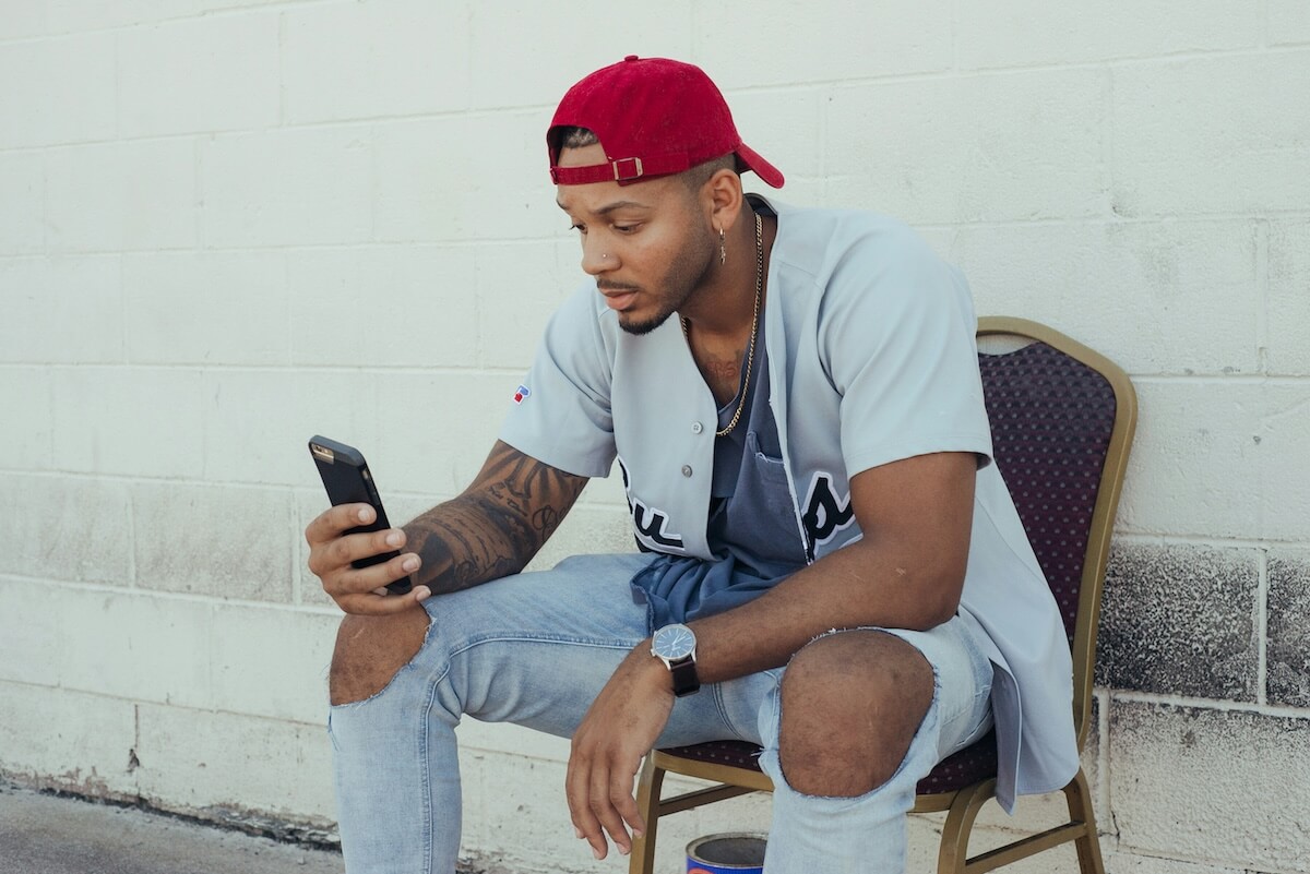 Unsplash: Man sitting outdoors in the summer texting by Darius Norwood