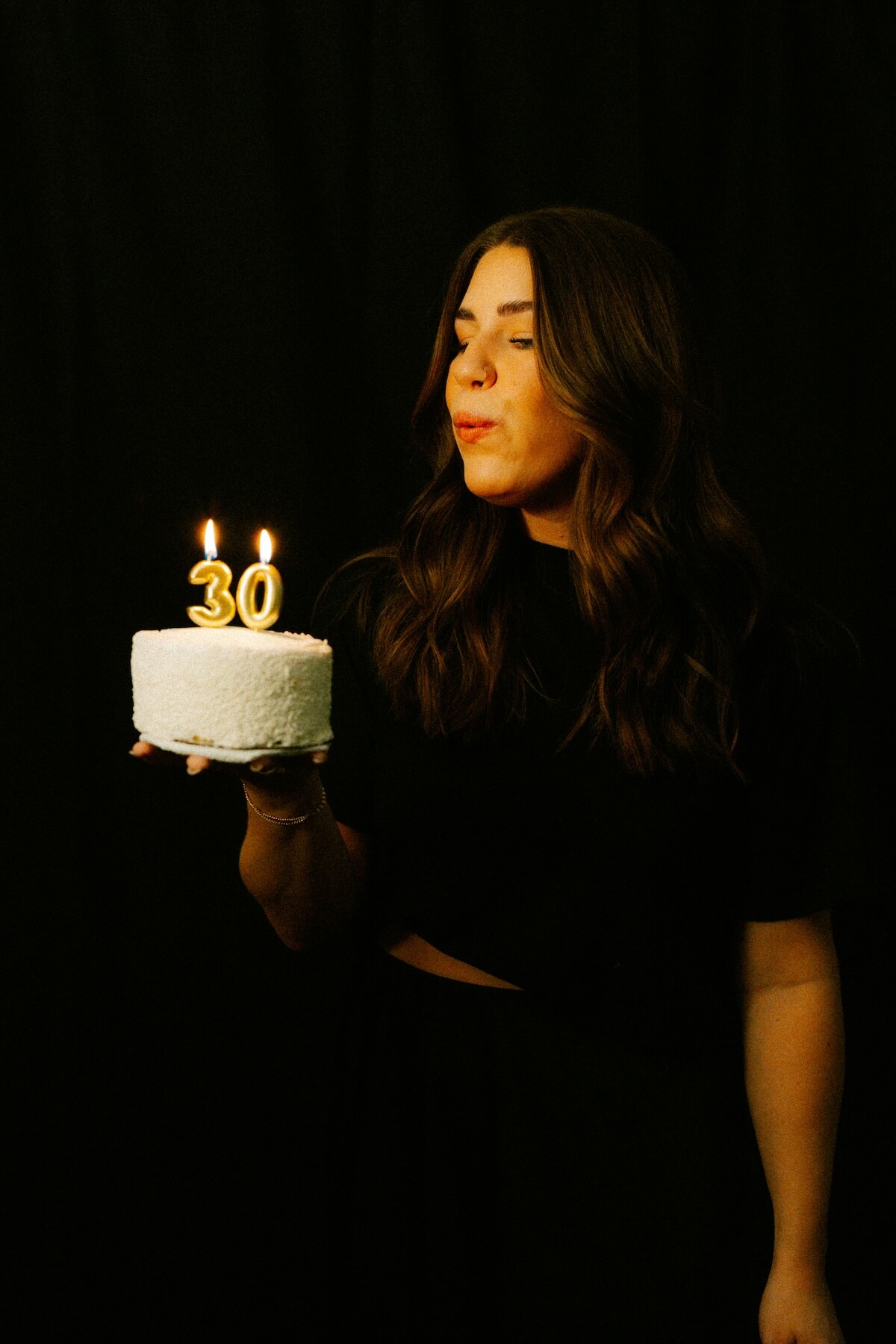 Unsplash: Woman blowing out candles on 30th birthday cake by Brooke Balentine