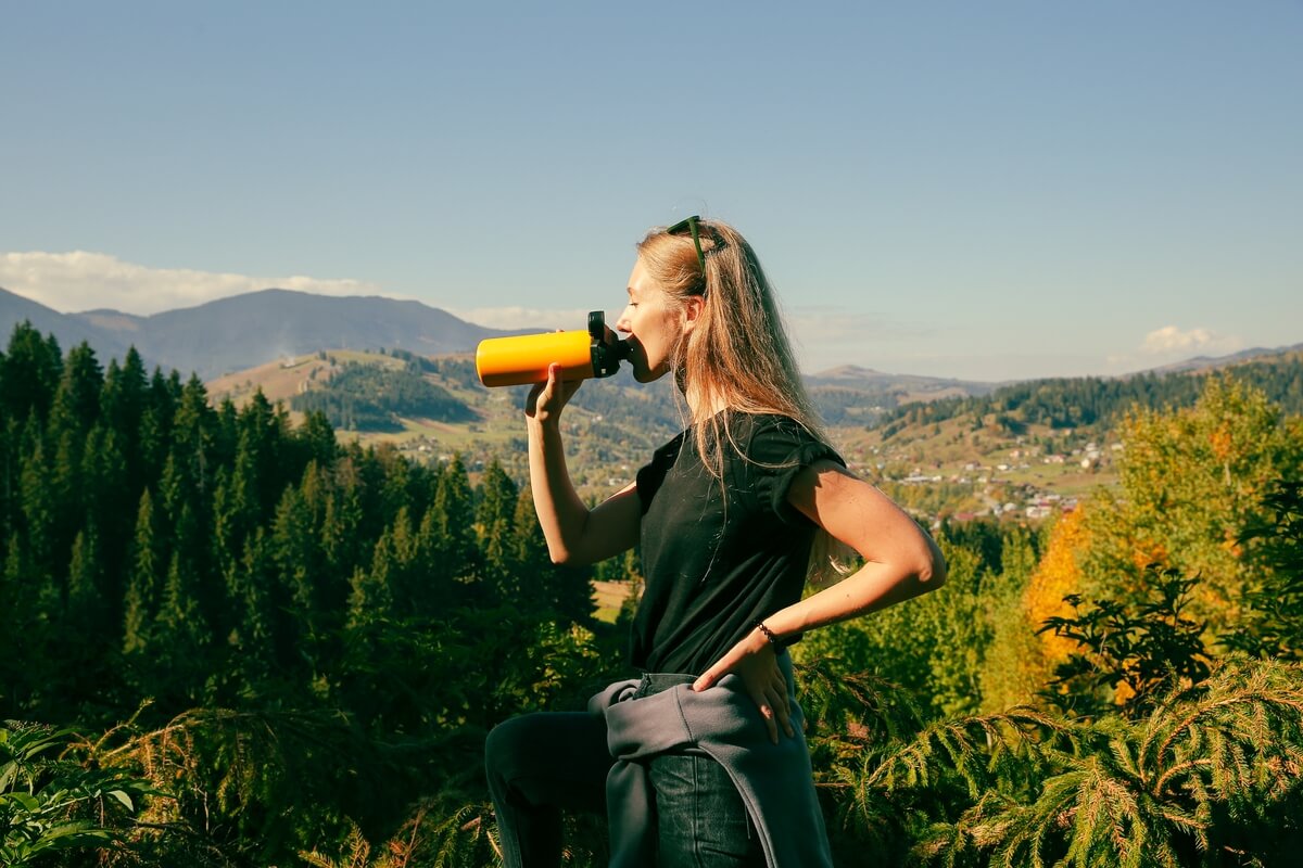 woman drinking water while hiking