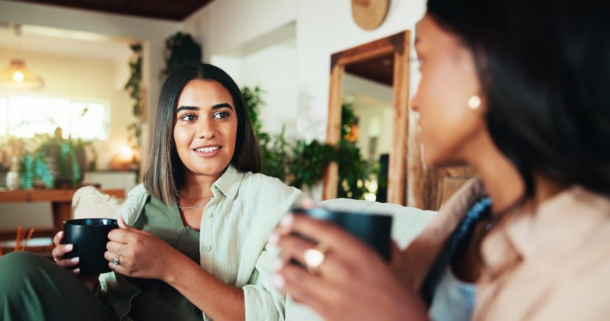 Shutterstock: Advice, coffee and friends with women on sofa for bonding, relax and social reunion. Discussion, caffeine and drink with people talking in living room at home for chat, news and connection together