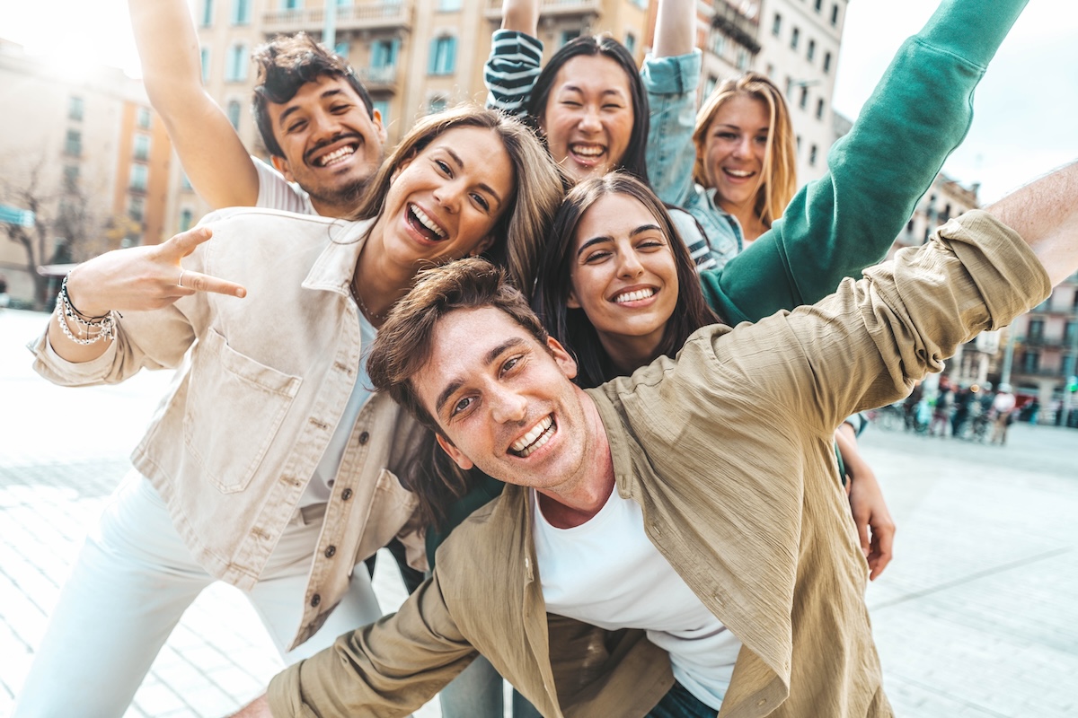Shutterstock: Multiracial best friends having fun outside - Group of young people smiling at camera outdoors - Friendship concept with guys and girls hanging out on city street