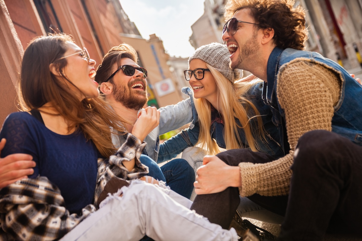 Shutterstock: Group of friends sitting on street laughing and talking