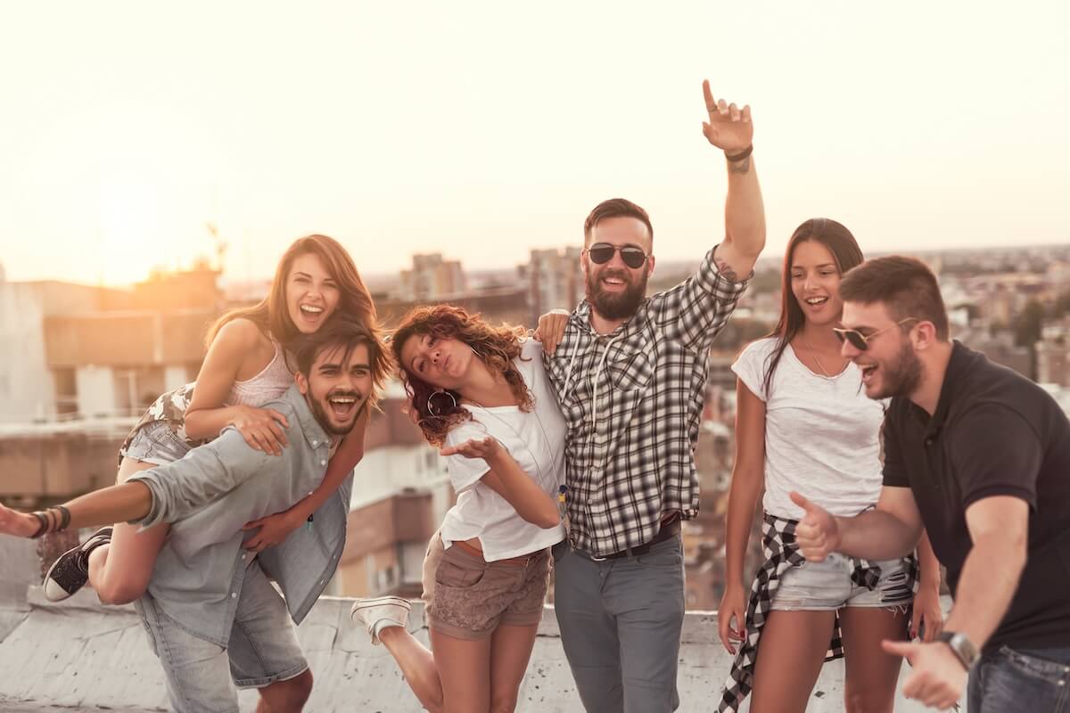 Shutterstock: Group of young people having fun at a summertime rooftop party, at sunset. Focus on the people in the middle