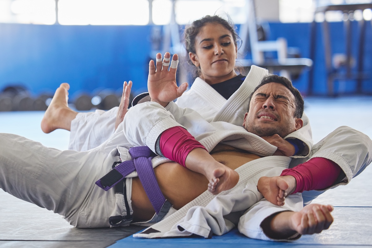 Shutterstock: Shes got him right where she wants him. Cropped shot of two young martial artists practicing jiu jitsu in the gym.