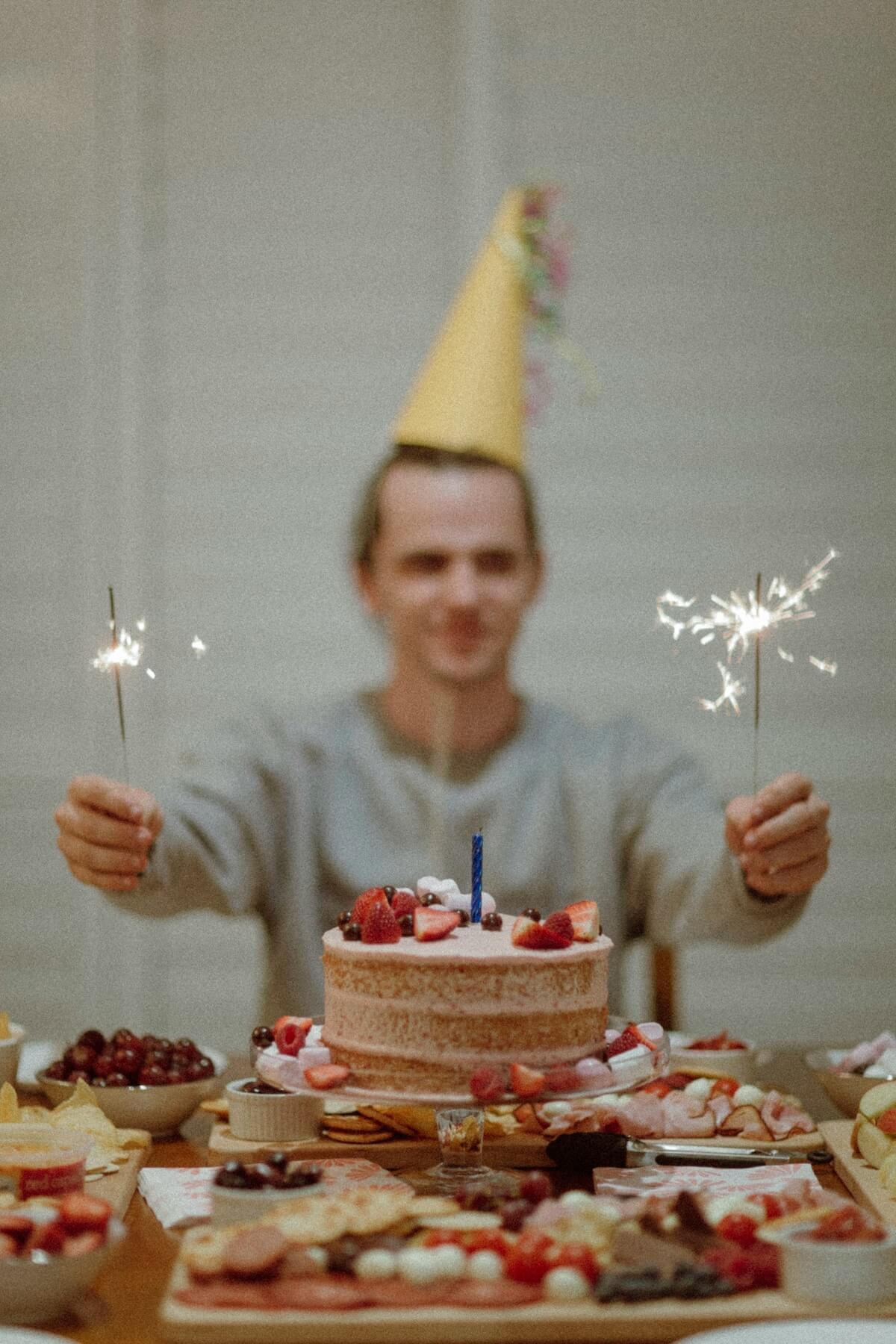 Unsplash: Man with birthday hat and cake with sparklers by Kyle Head