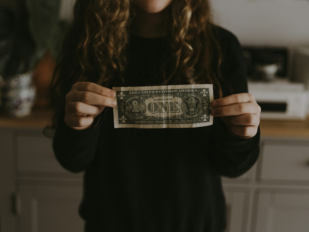 Unsplash: Person holding up one dollar bill by Annie Spratt