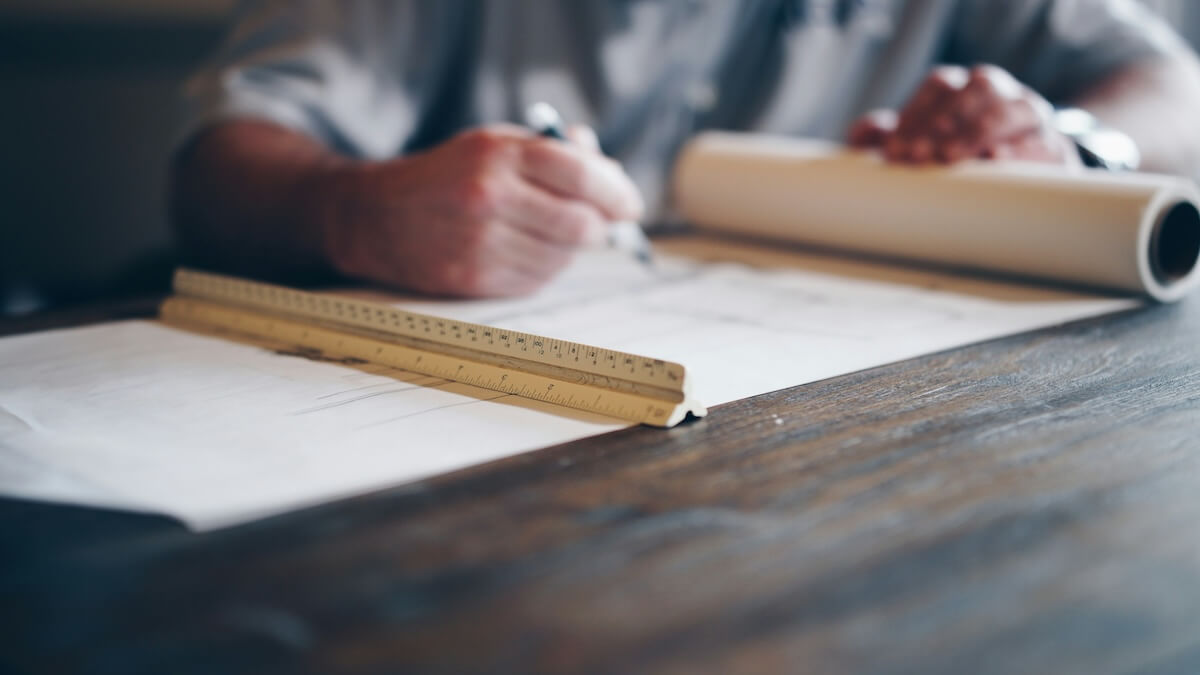 Unsplash: Person writing on blueprints by Daniel McCullough