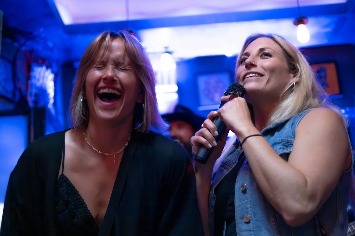 Unsplash: Two women laughing singing karaoke by Cord Allman
