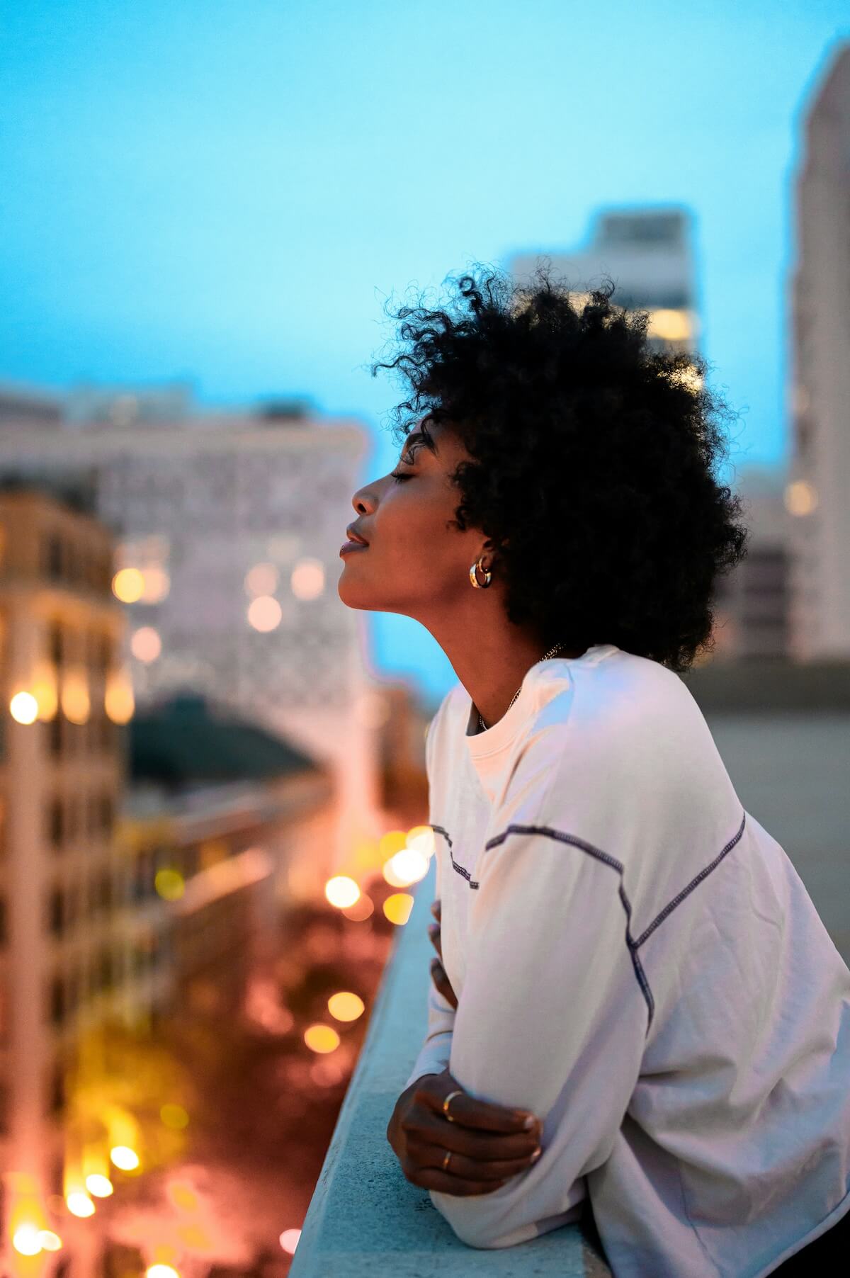 Unsplash: Woman happy with closed eyes on city balcony by Jeffery Erhunse