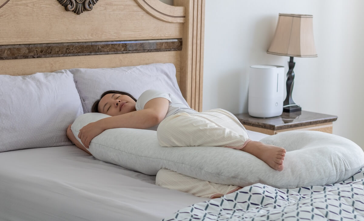 Shutterstock: Woman sleeping and using body pillow