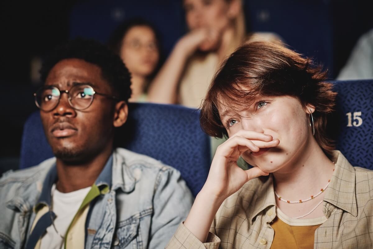 Shutterstock: Medium close-up portrait of young Black mana and Caucasian woman spending evening together crying while watching tragedy movie at cinema
