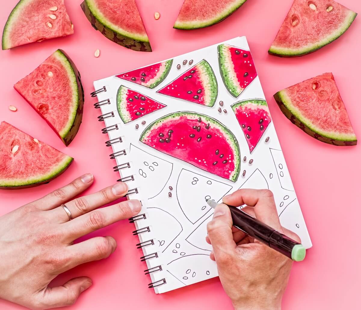 Shutterstock: woman hands drawing a watermelon pattern sketch on pink background with markers. bright food sketch decorated with watermelon pieces