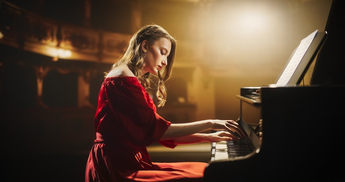 Shutterstock: Classical Piano Concert: Under the Spotlight, Young Female Pianist in a Red Dress Delivering a Powerful Performance on the Grand Piano. Elegant Stage Setting Complements Her Passionate Playing