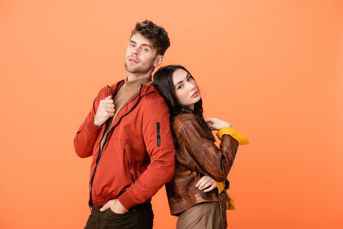 Shutterstock: trendy couple in leather jackets looking at camera while posing isolated on orange