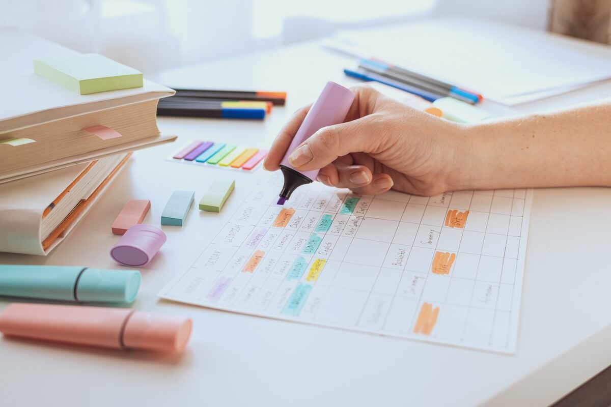 Shutterstock: A woman's hand draws with a marker or purple text highlighter on a sheet with a schedule. Student workplace. Planning the week. Time management of pupil and student.