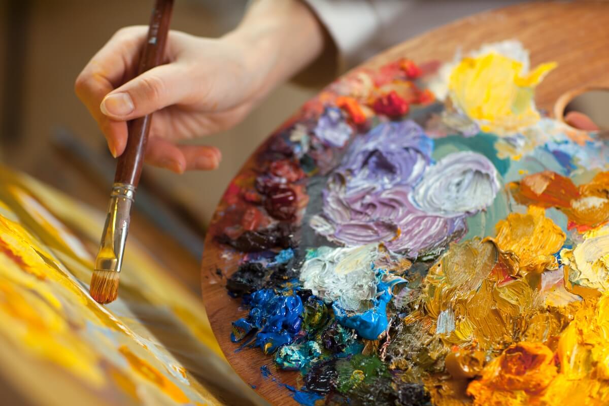 Shutterstock: artist paints a picture of oil paint brush in hand with palette closeup