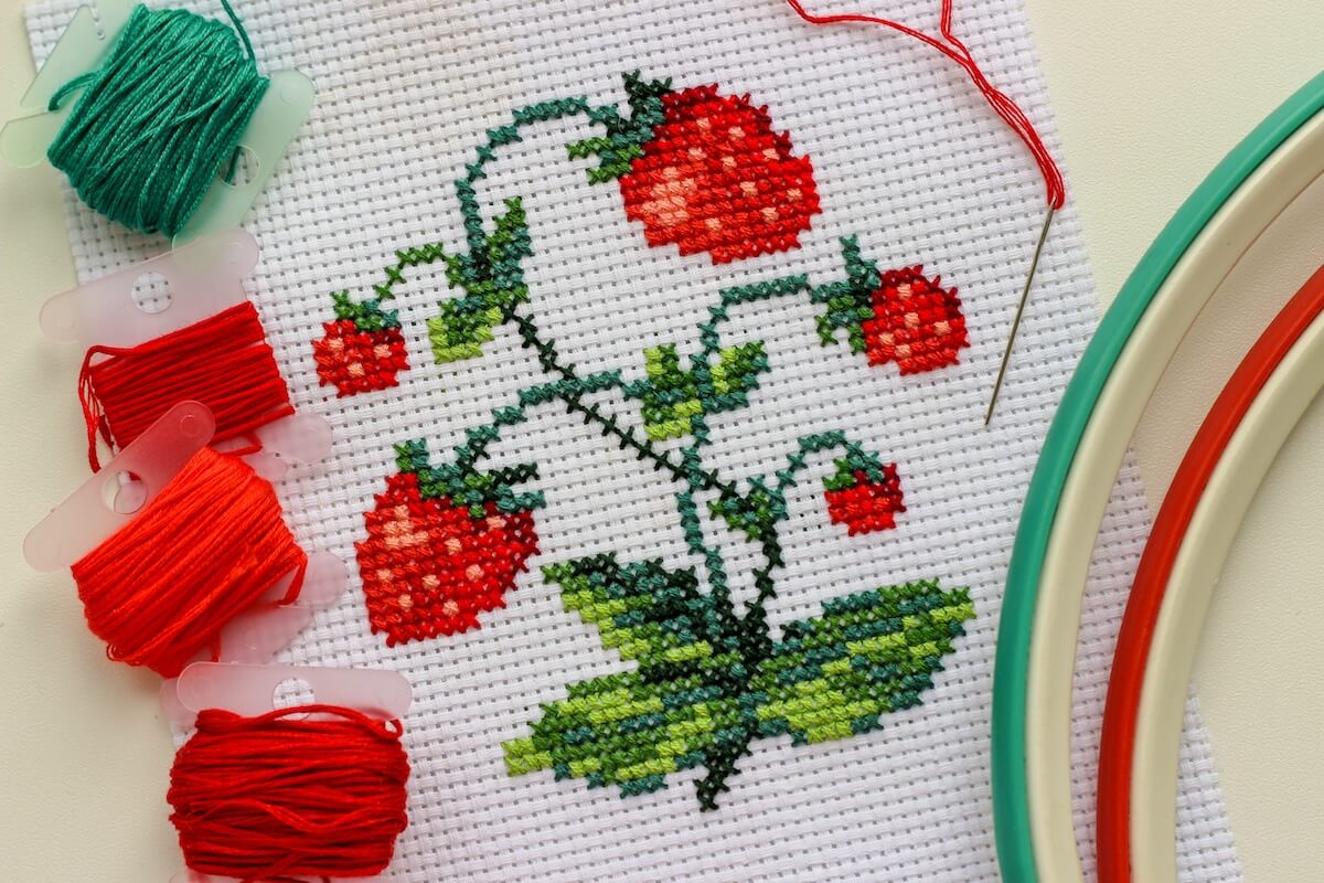 Shutterstock: Red ripe strawberries embroidered with a cross-stich on a white canvas by hand. With a needle, thread floss and hoop.