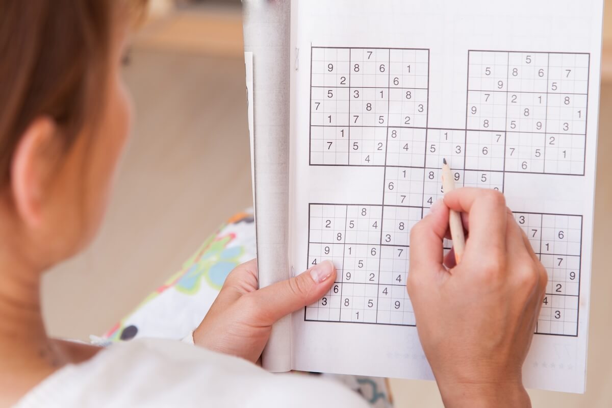 Shutterstock: Young beautiful woman doing crosswords in room