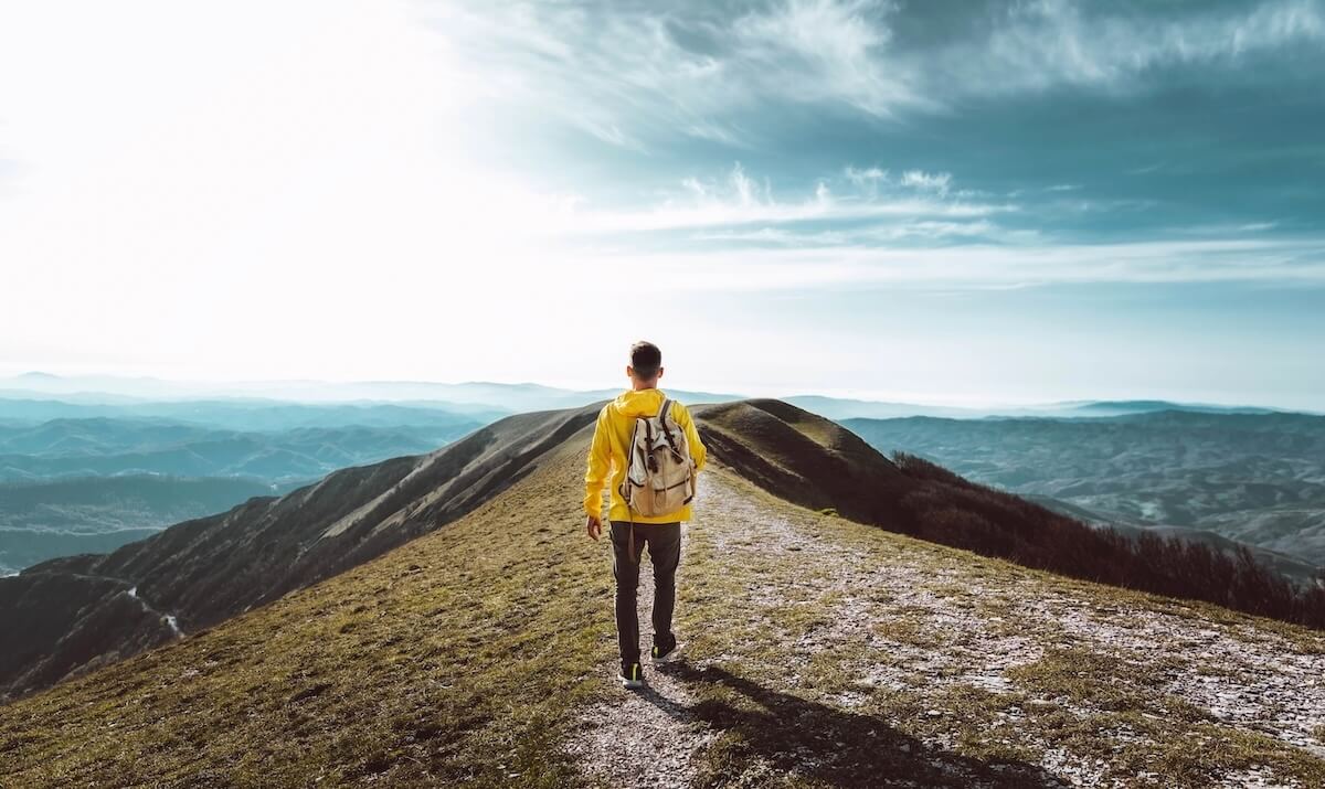 Shutterstock: Young man with backpack hiking mountains - Hiker having trekking day out on a sunny day - Successful, sport and inspirational concept