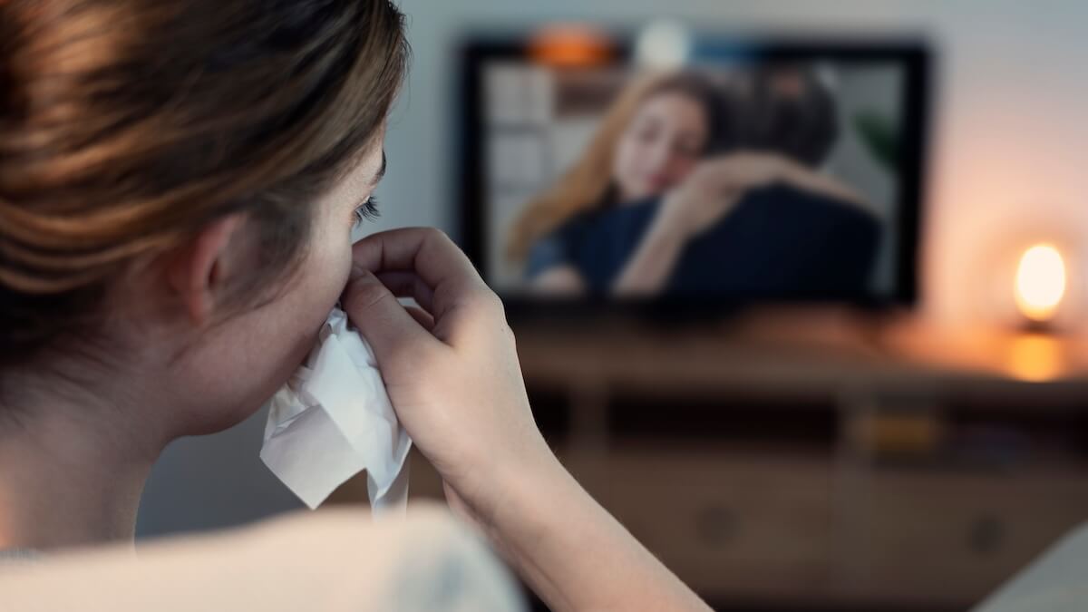 Shutterstock: Woman crying while watching tv in the night
