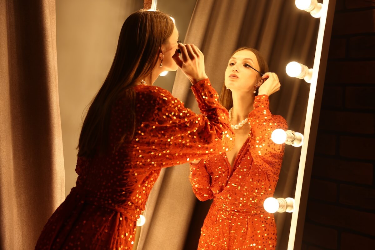 Shutterstock: Beautiful woman applying mascara while getting ready near mirror indoors