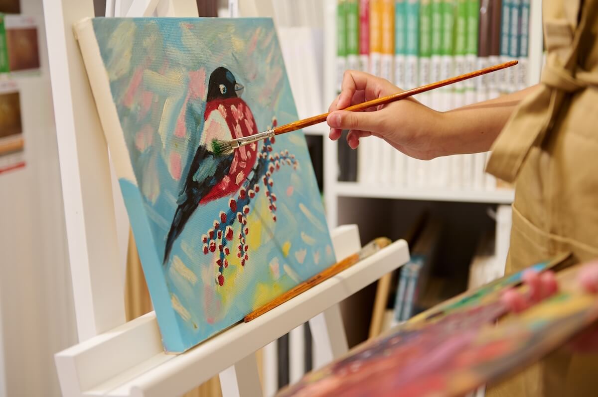 Shutterstock: Close-up of the hand of a child holding a paintbrush, drawing with oil or acrylic paints on canvas in a creative workshop. Painting. People. Creative hobby for children. Learning fine art. Education