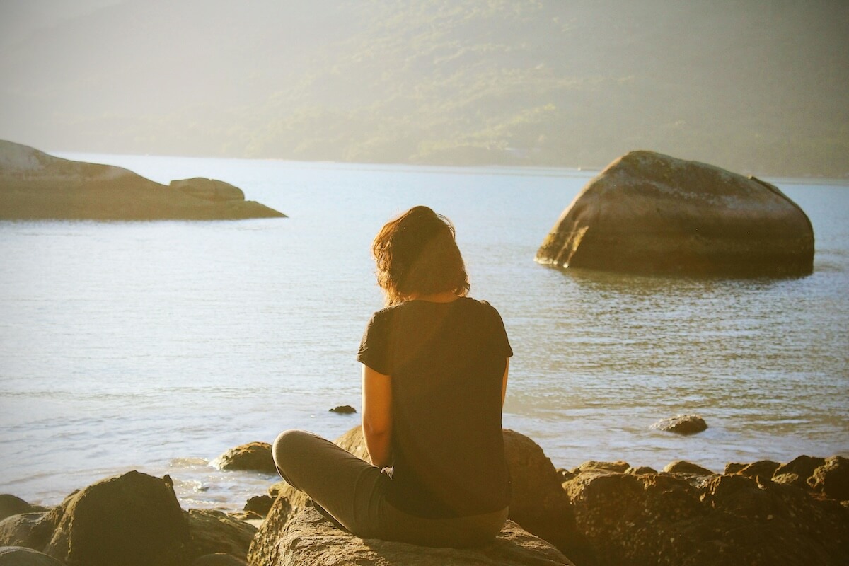 Unsplash: woman sitting thoughtfully near water by Lua Valentia