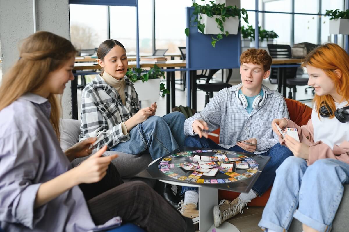 Shutterstock: group of young friends playing board games together while sitting around table.